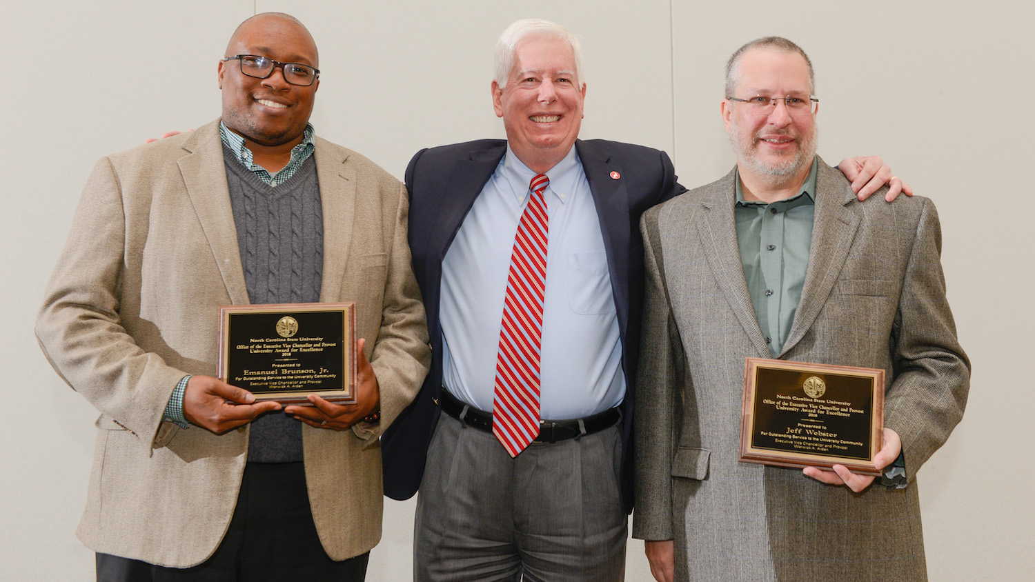 Brunson and Webster smiling with Tom Miller and holding plaques.