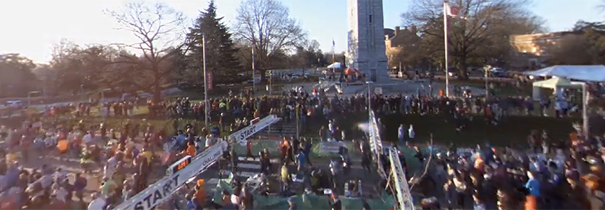 Runners pass through the starting line in front of the NC State Bell Tower.