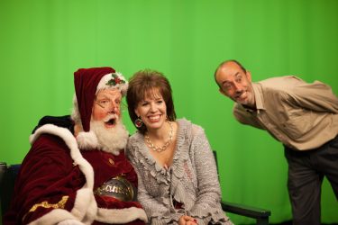 Picture of two people posing with Santa Claus